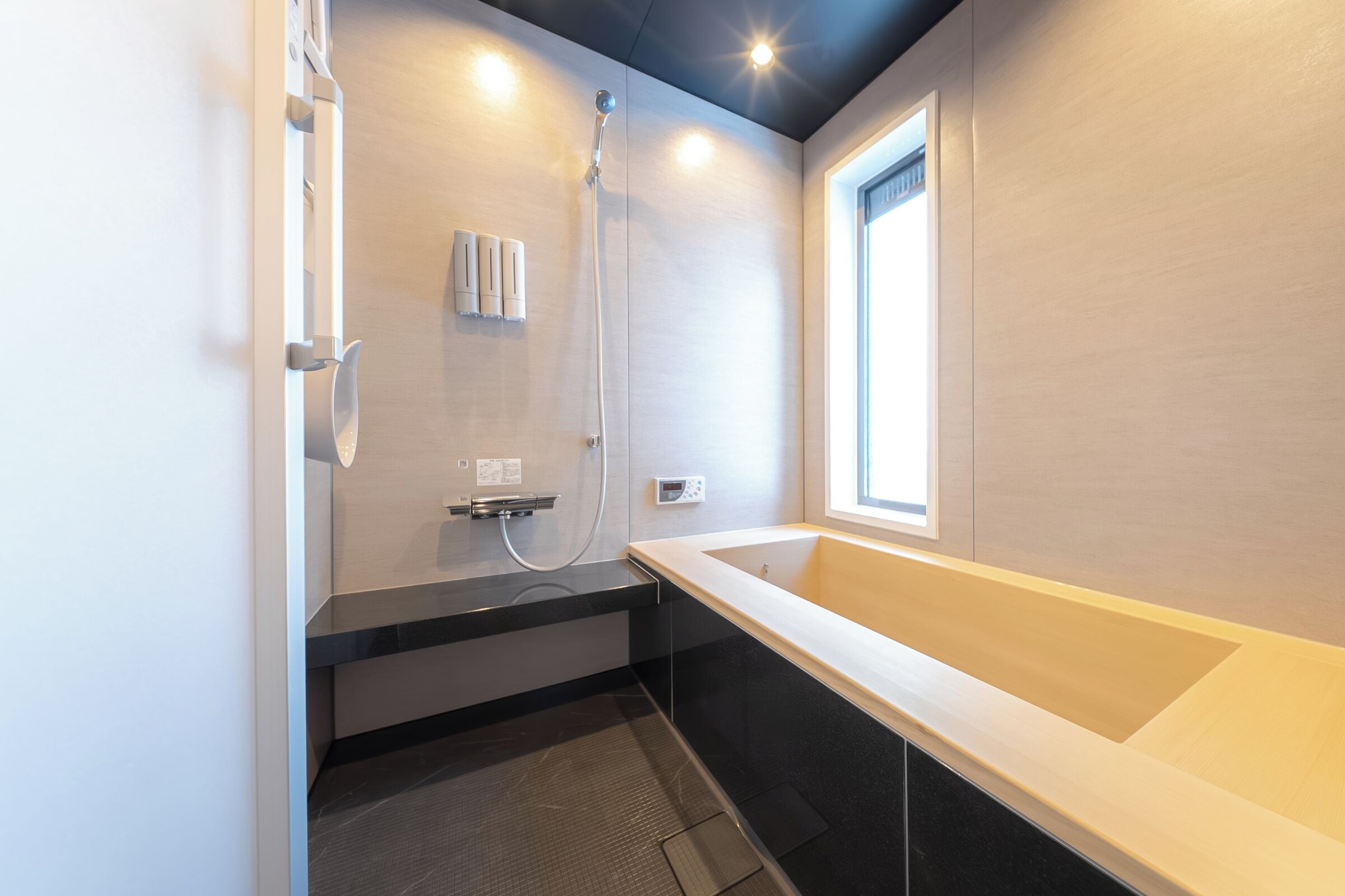 A modern bathroom with a bathtub, shower, and a window providing natural light.