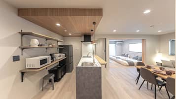 A modern kitchen with a central island, built-in appliances, and a dining area with a table and chairs.