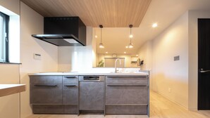 A modern kitchen with a central island, built-in dishwasher, and a black range hood. - Hotel Bokusyusou Tokyo (Tokyo)