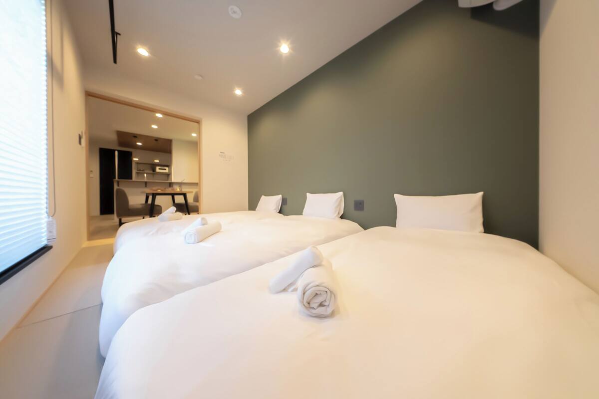 Habitación de hotel con dos camas, kitchenette y vista al comedor.
