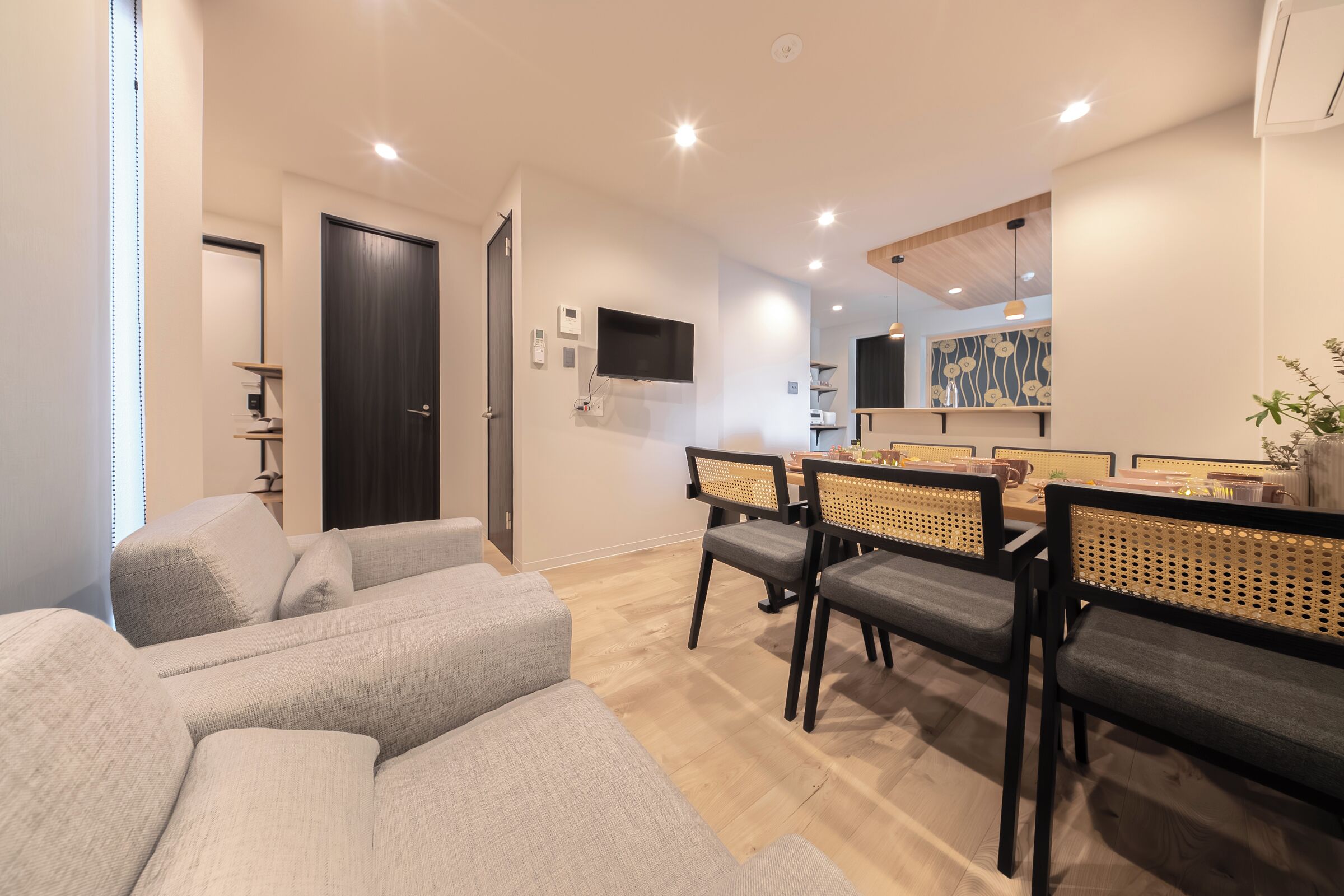 A modern living room with a sofa, dining table, chairs, and a TV.