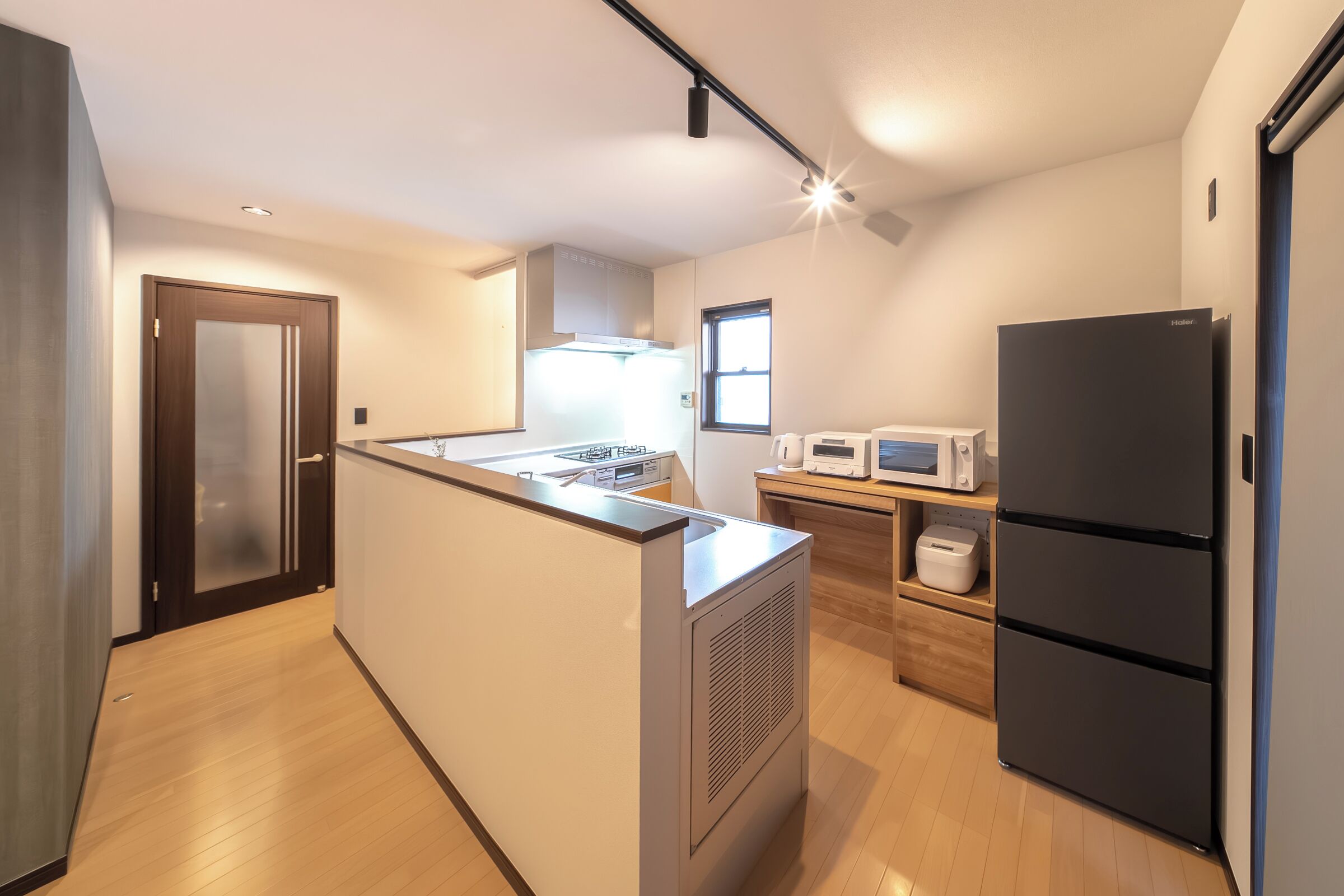 A modern kitchen with a central island, built-in microwave, and a black refrigerator.