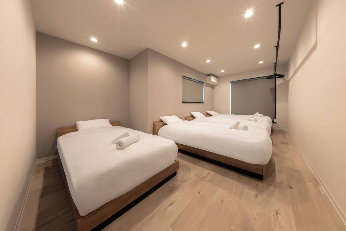 Habitación de hotel con dos camas, piso de madera y aire acondicionado instalado en la pared.