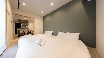 A hotel room with two beds, a dining area, and a kitchenette.