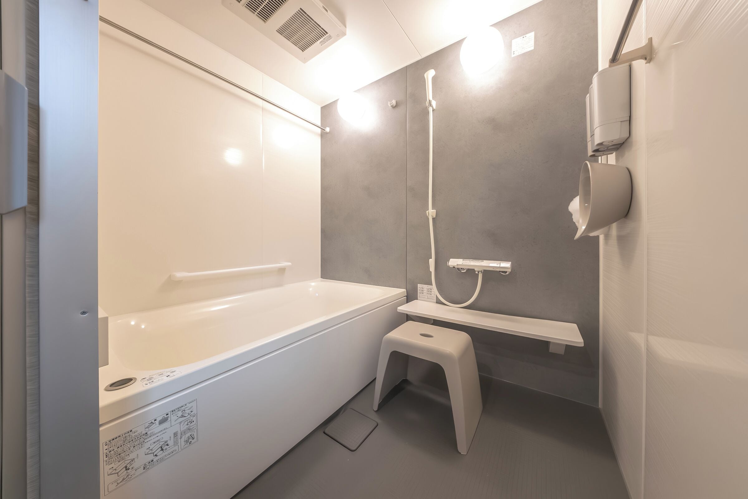 Un baño moderno con bañera, ducha, inodoro y un taburete pequeño.