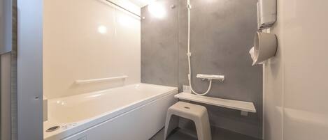 Un baño moderno con bañera, ducha, inodoro y un taburete pequeño.