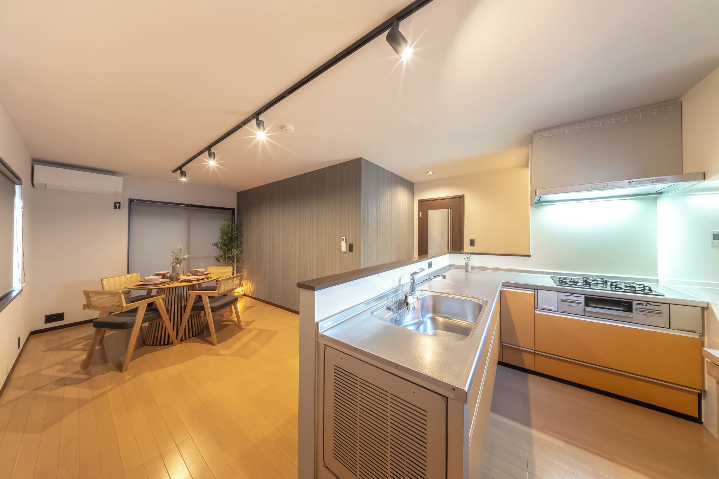 A modern kitchen with a built-in stove, a sink, and a dining area with a table and chairs.