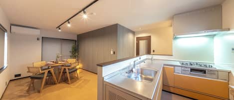 A modern kitchen with a built-in stove, a sink, and a dining area with a table and chairs.