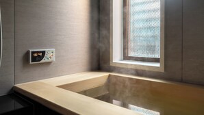 A modern bathroom with a wooden bathtub, a control panel, and a window with a view. - Hotel Bokusyusou Tokyo (Tokyo)