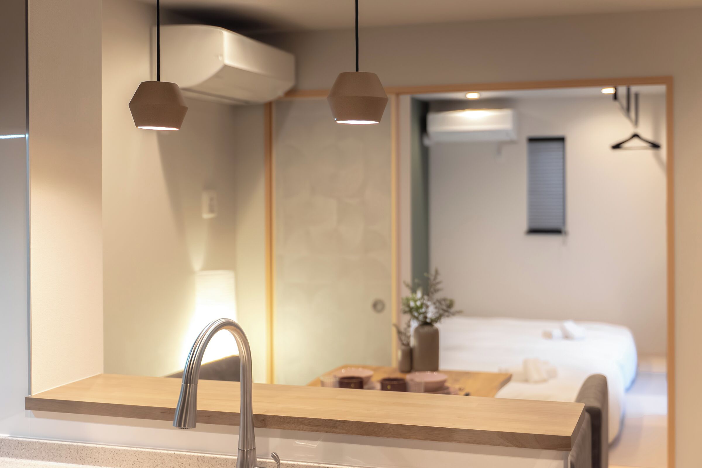 A modern bathroom with a sink, mirror, and pendant lights.
