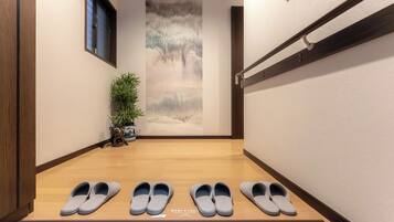 A hallway with a wooden floor, a wall-mounted rack, and a potted plant.