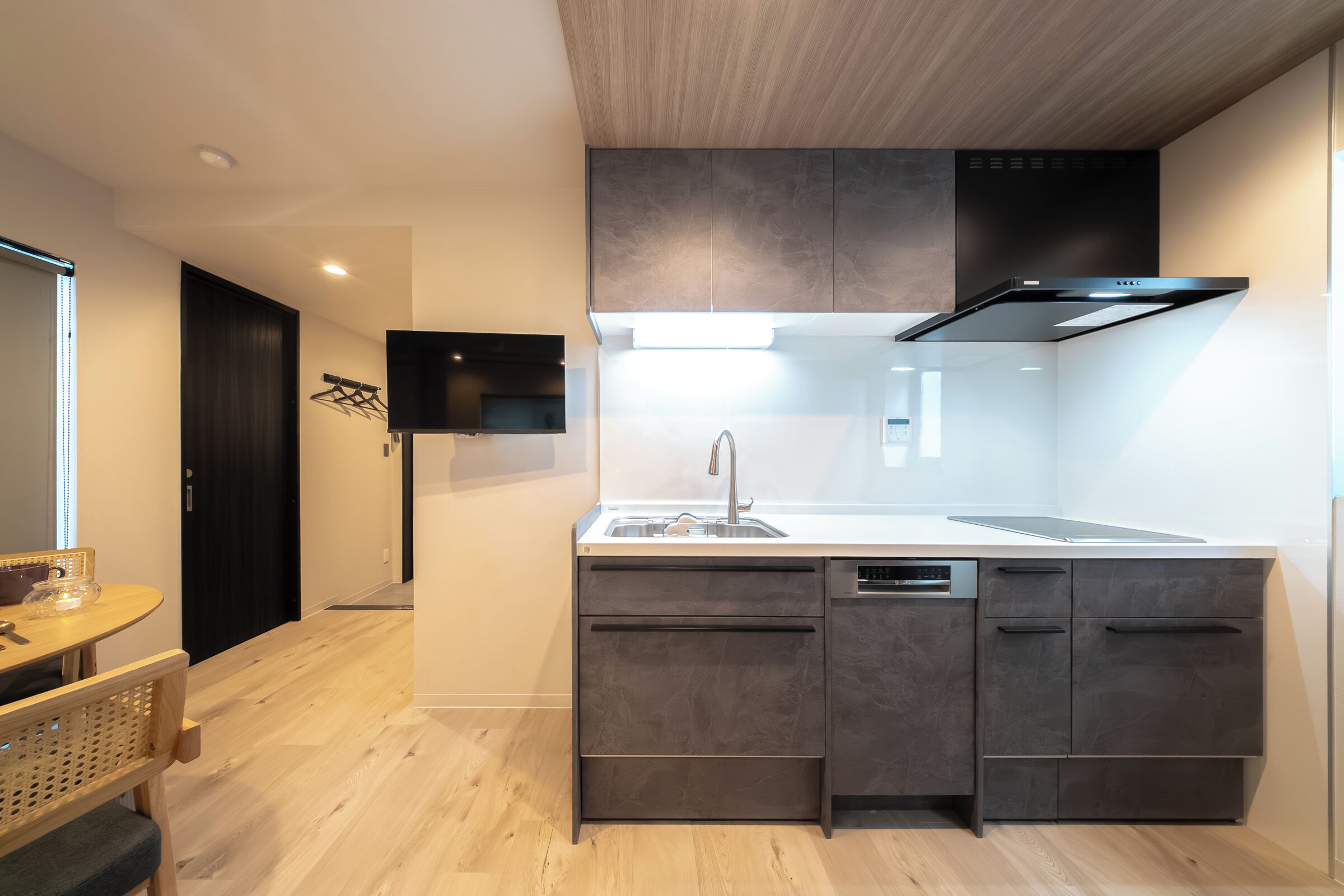 A modern kitchen with a built-in dishwasher, a large island with a sink, and a flat-screen TV mounted on the wall.