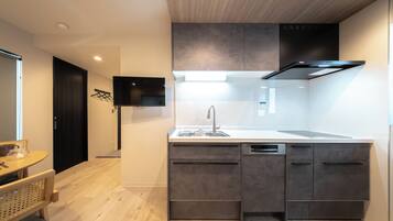 Una cocina moderna con lavavajillas integrado, una isla grande con pileta y un televisor de pantalla plana montado en la pared.