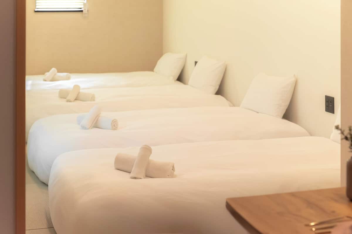 Una habitación de hotel con tres camas, cada una con toallas ordenadamente dobladas.