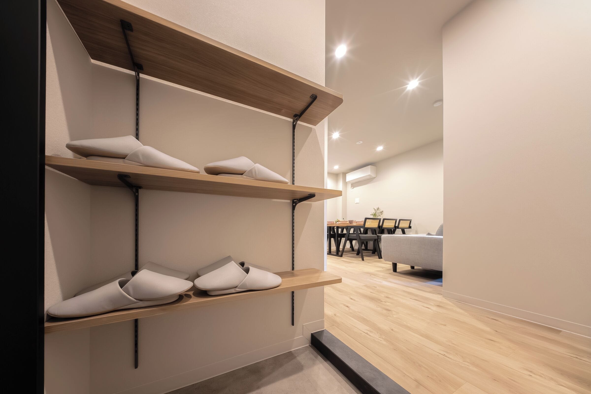 Un intérieur moderne avec des étagères en bois où sont exposées des chaussons, un coin repas avec des tables et des chaises, et un canapé.