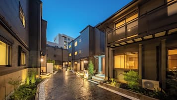 A modern building with a paved courtyard, outdoor lighting, and a visible air conditioning unit.