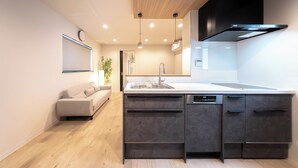 A modern kitchen with a central island, built-in appliances, pendant lighting, and a minimalist design. - Hotel Bokusyusou Tokyo (Tokyo)