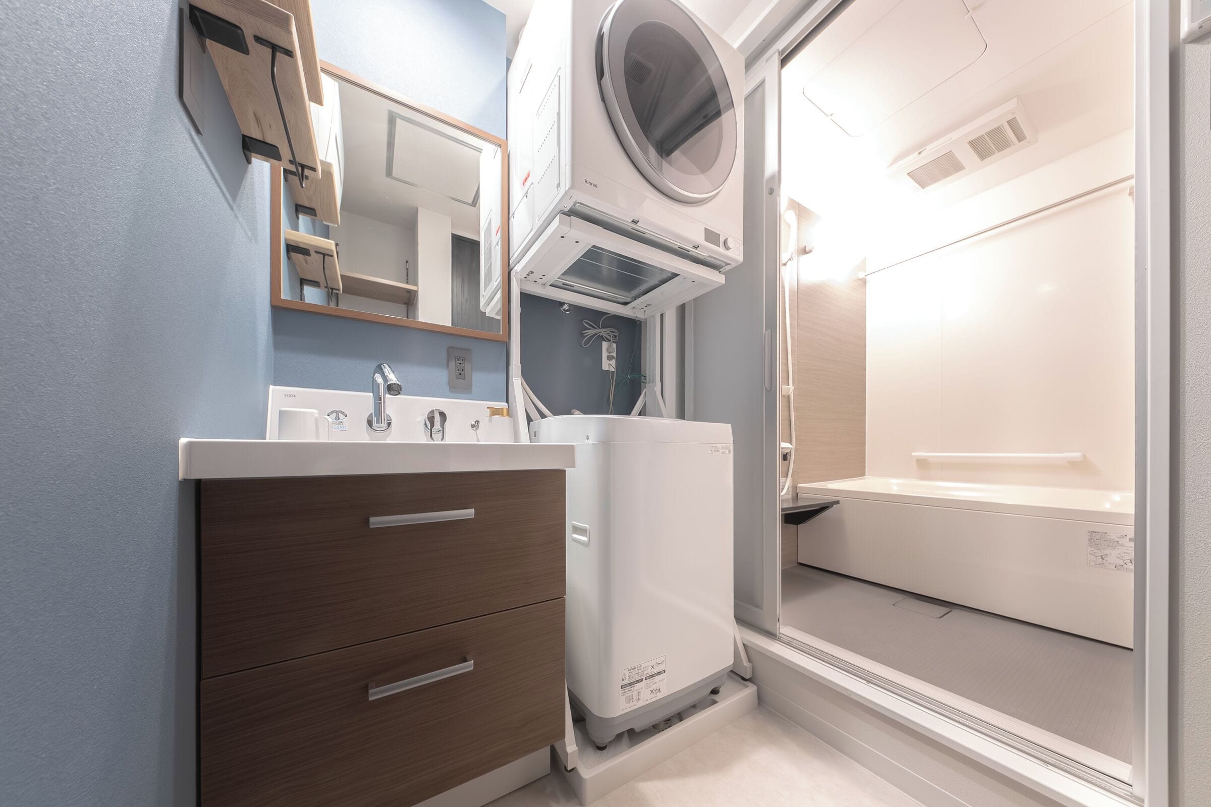 A modern bathroom with a built-in washer and dryer, a mirror, and a sink.