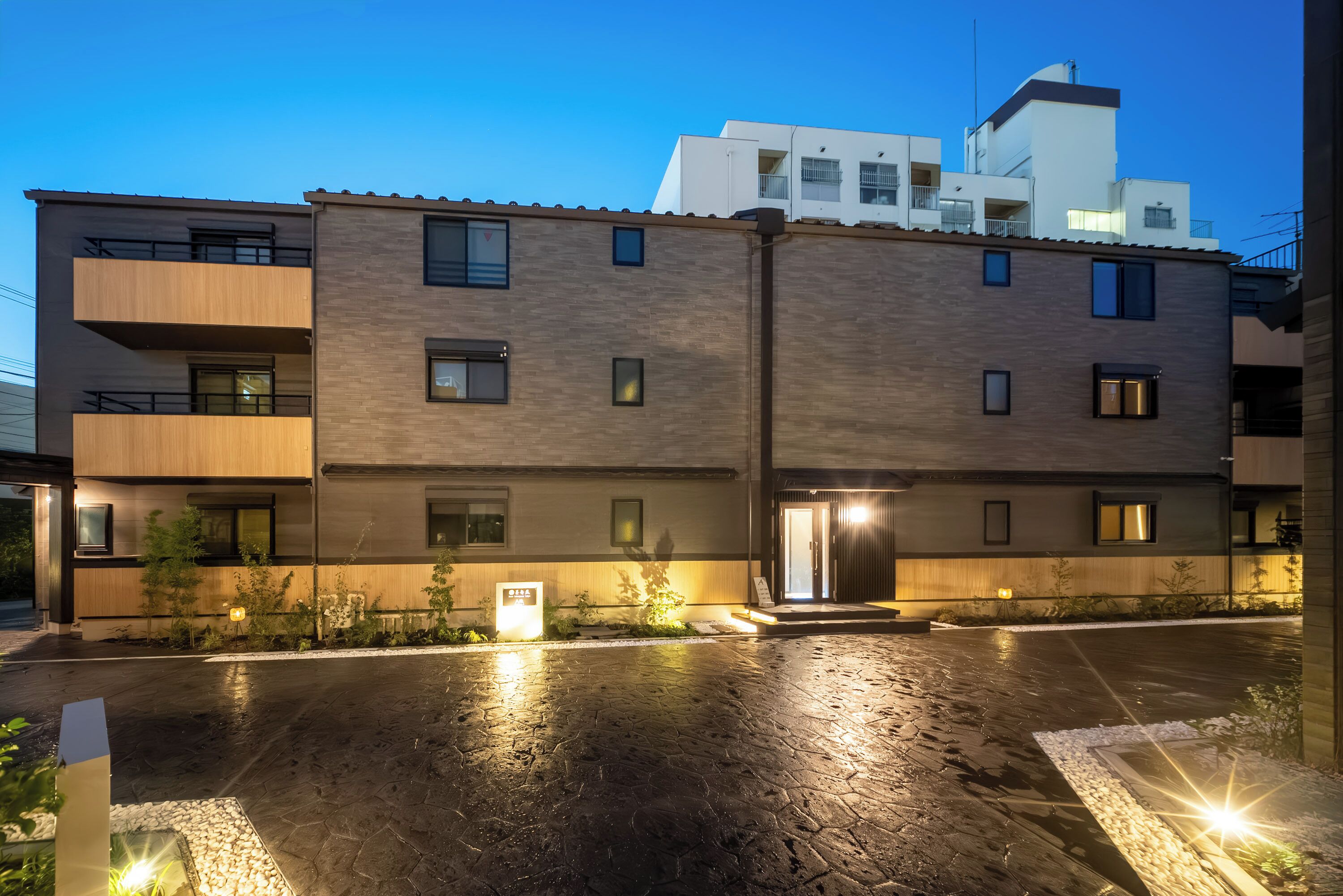 Un edificio moderno de varios pisos con el suelo mojado, probablemente por lluvia reciente.