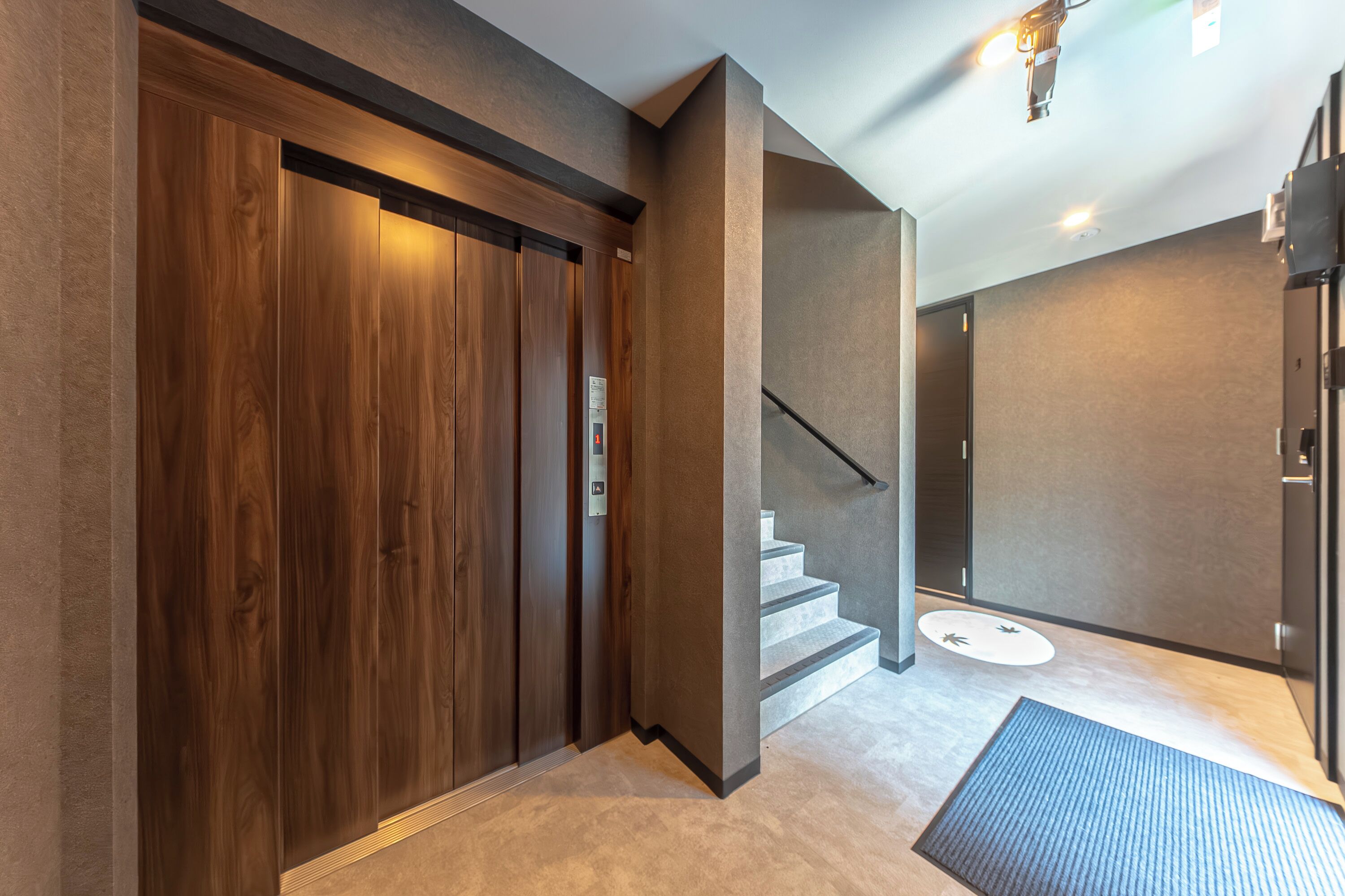 Ein moderner Aufzug mit Holzvertäfelung, eine Treppe mit geometrischem Design und ein strukturierter Boden.