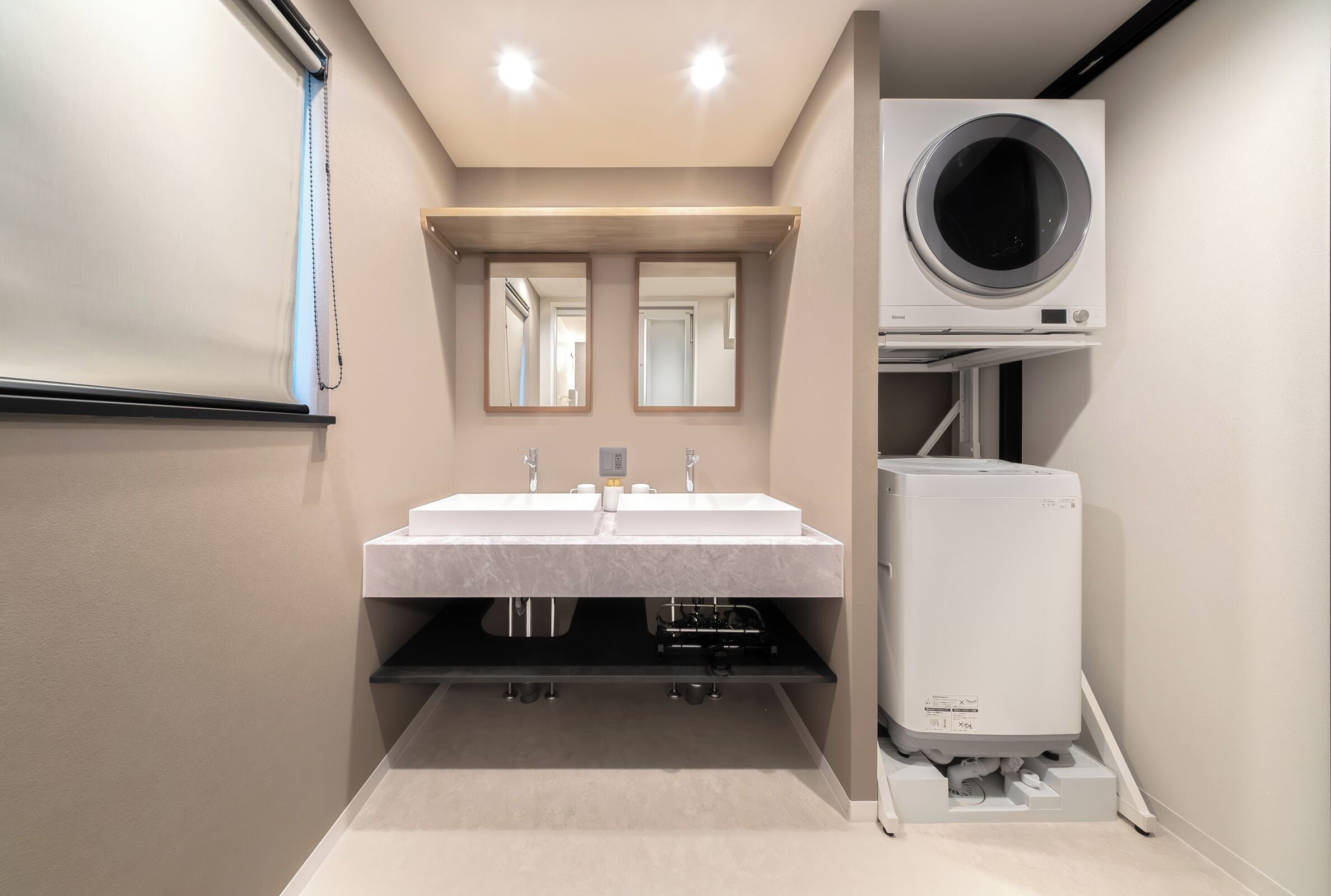 Un baño moderno con lavamanos doble, un espejo y lavadora y secadora integradas.