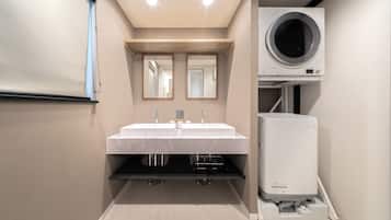 Un baño moderno con lavamanos doble, un espejo y lavadora y secadora integradas.