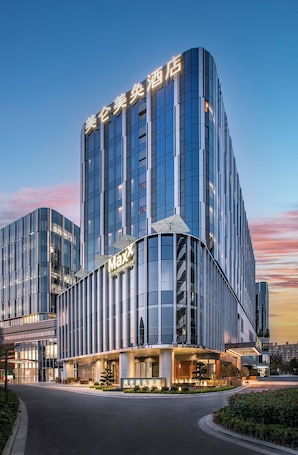 A modern hotel with a curved facade, large windows, and a prominent 'Maxx' sign.