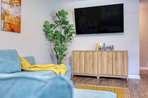 A living room with a sofa, a television, a wooden cabinet, and a plant. - Kings w/Pool & Grill, 15 mins to Fort Benning (Columbus)