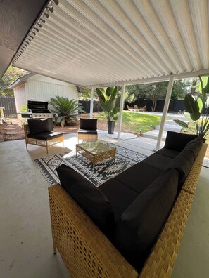 An outdoor patio with a wicker sofa, a glass-top coffee table, and a grill. - Kings w/Pool & Grill, 15 mins to Fort Benning (Columbus)