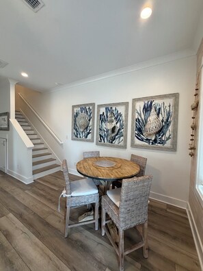 A dining area with a round table, wicker chairs, and three framed artworks on the wall. - August Dates Available-Key Lime Cottage-Pet Friendly-Snowbird Wanted!! (Orange Beach)