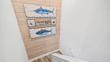 A wooden wall with three nautical-themed signs, a white staircase, and a wooden floor.