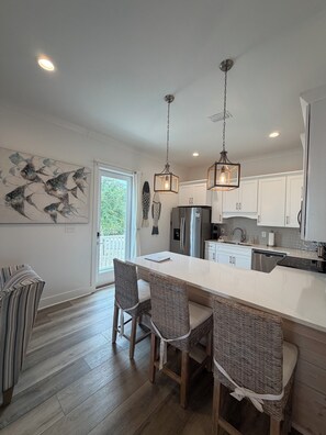 A modern kitchen with a central island, two hanging pendant lights, and a view to the outside. - August Dates Available-Key Lime Cottage-Pet Friendly-Snowbird Wanted!! (Orange Beach)