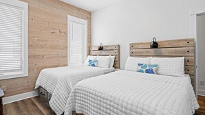 A bedroom with two beds, wooden headboards, white bedding, and a wooden wall.