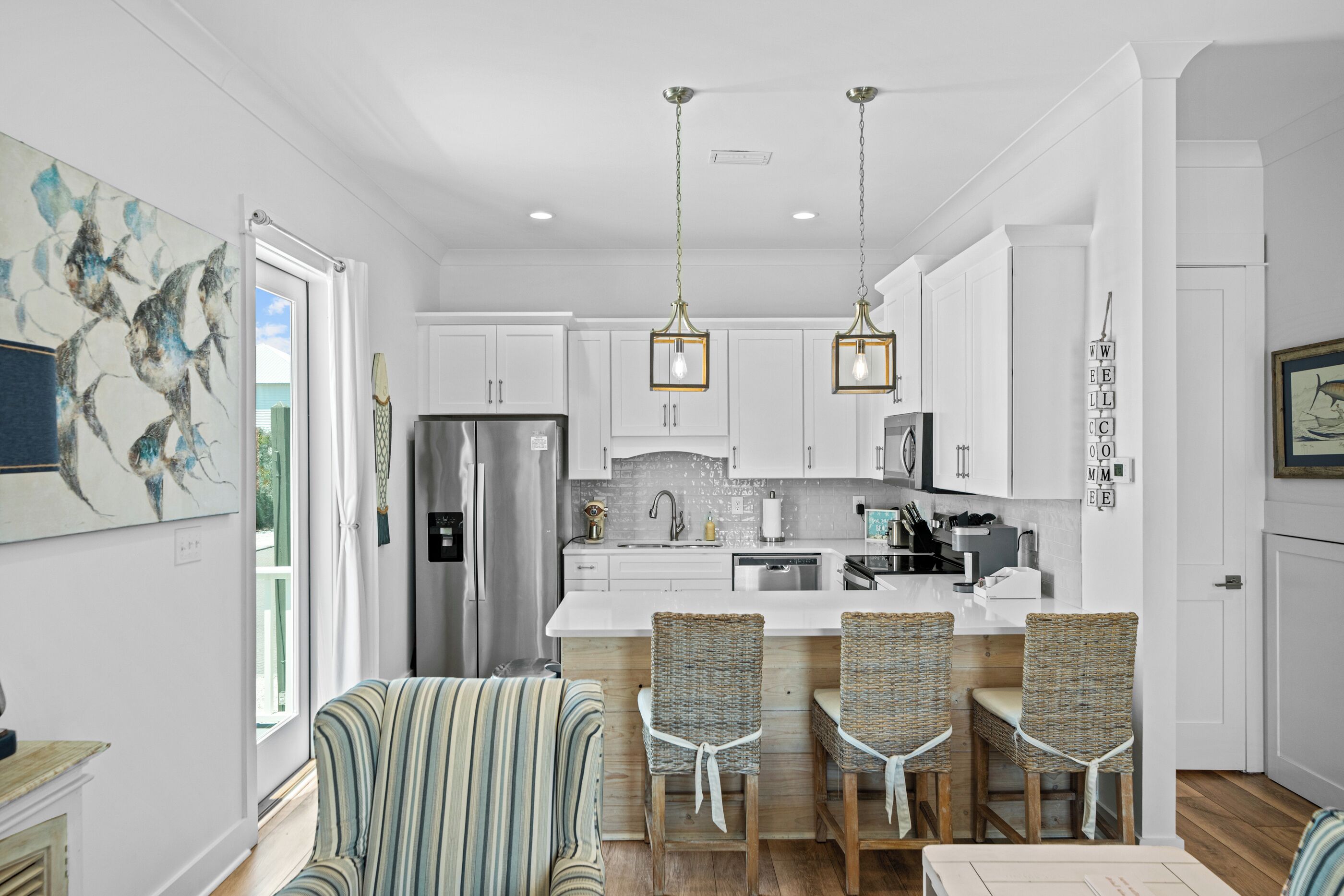 A modern kitchen with white cabinets, stainless steel appliances, and a central island with bar stools.