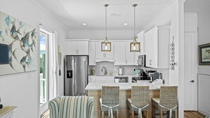 A modern kitchen with white cabinets, stainless steel appliances, and a central island with bar stools.