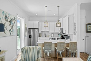 A modern kitchen with white cabinets, stainless steel appliances, and a central island with bar stools.