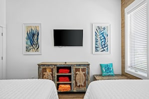 A bedroom with two beds, a television, and artwork on the wall.
