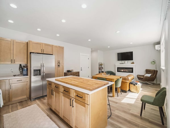 Una cocina moderna con armarios de madera, un refrigerador de acero inoxidable y una isla también de madera.
