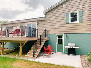 A two-story house with a covered deck, a grill, and outdoor seating.