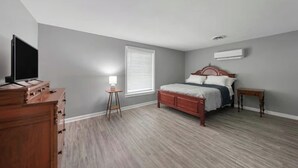 Une chambre à coucher avec un lit, une commode, une lampe et un téléviseur.