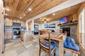 A kitchen with wooden cabinets, a stone fireplace, and a dining area with a blue cushioned bench.