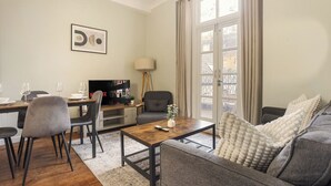 Un salon comprenant un canapé, une table basse, un téléviseur et un coin repas avec des chaises et une table.