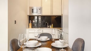 Un coin repas avec une table en bois dressée pour quatre personnes, un four à micro-ondes placé au-dessus du comptoir et une fenêtre offrant une vue agréable.