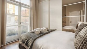 Une chambre avec une grande fenêtre, un lit avec une couverture et une armoire.