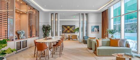A modern hotel lobby with a central dining area, seating arrangements, and large windows offering views.