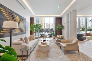 A modern hotel lobby with a sofa, armchairs, a coffee table, and a large window offering a view of the cityscape. - Exclusive 2BR in Brickell-Views & Top Amenities-Monthly Stay (Miami)