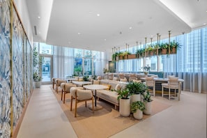 A modern interior with a sofa, chairs, tables, and potted plants. - Exclusive 2BR in Brickell-Views & Top Amenities-Monthly Stay (Miami)