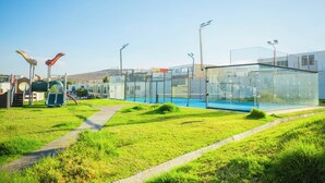 Ein modernes Gebäude mit Glasfassade, ein Spielplatz mit Rutschen und ein klarer Himmel.
