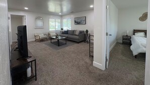 Una habitación con televisión, sofá, mesa de centro y cama.