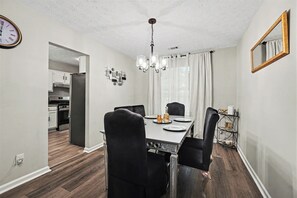 Ein Essbereich mit Tisch, Stühlen, einer Chandelier und einer Küche im Hintergrund.